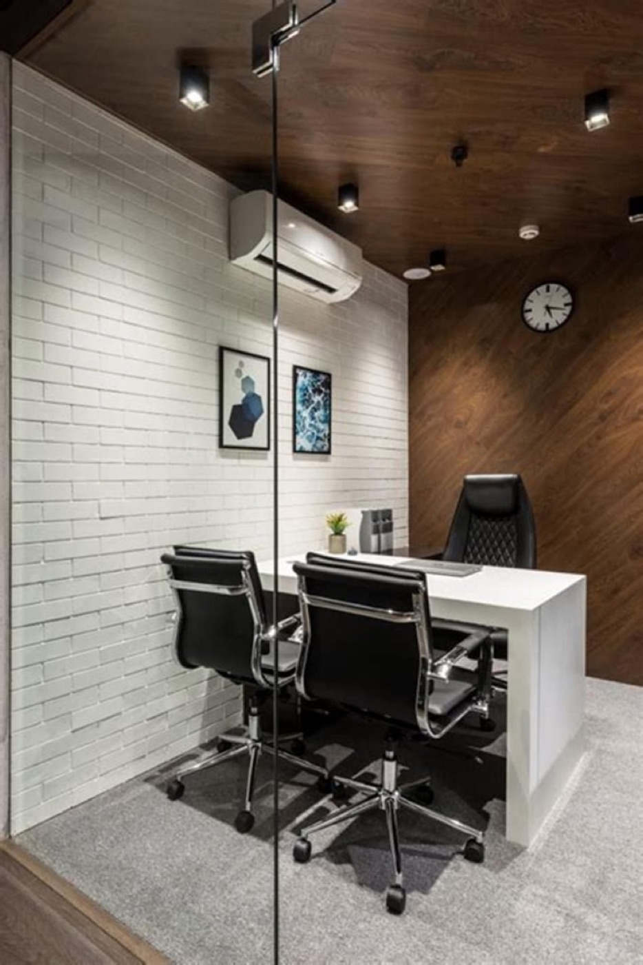 A cabin with a white brick wall, timber ceiling and black office chairs