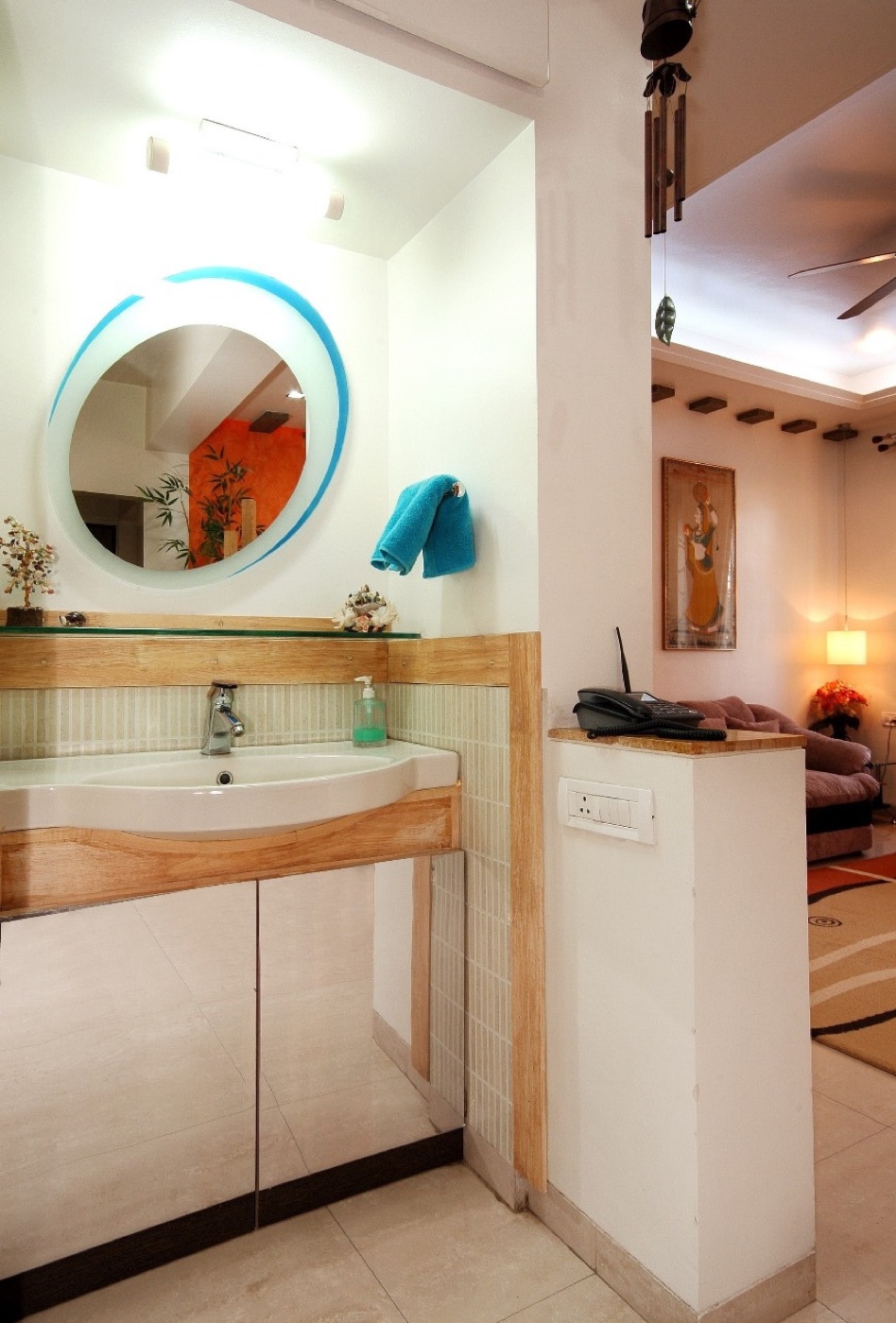 A wash basin with a round backlit mirror and timber panelling